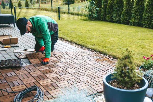 A man worker laying wooden flooring on the terrace at home