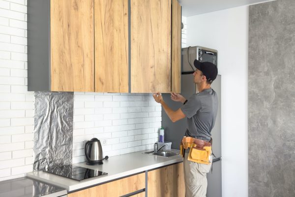 The carpenter finalizing the assembly of the kitchen shelf on the wall. High quality photo